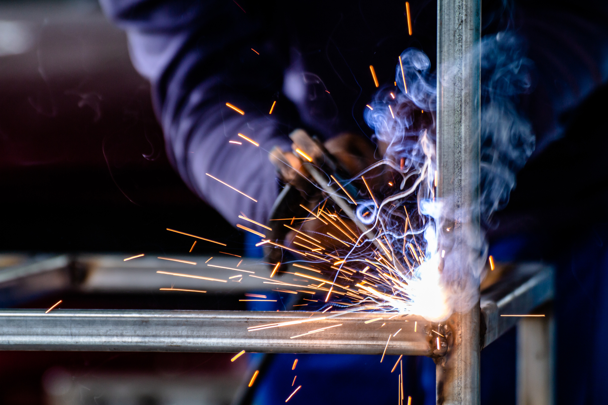 Person welding metal with bright sparks.