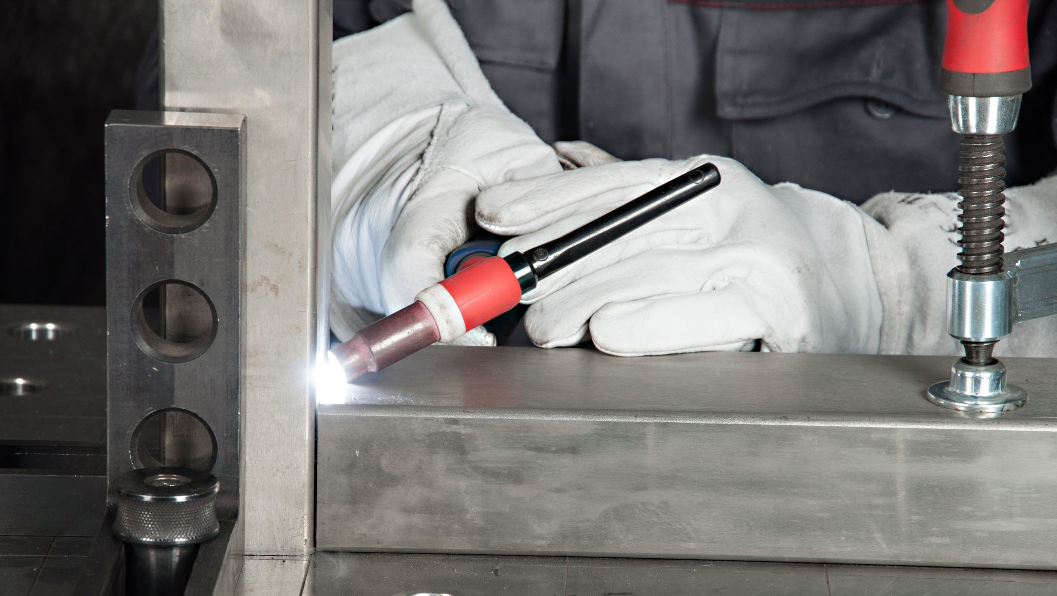 Worker welding metal with protective gloves.