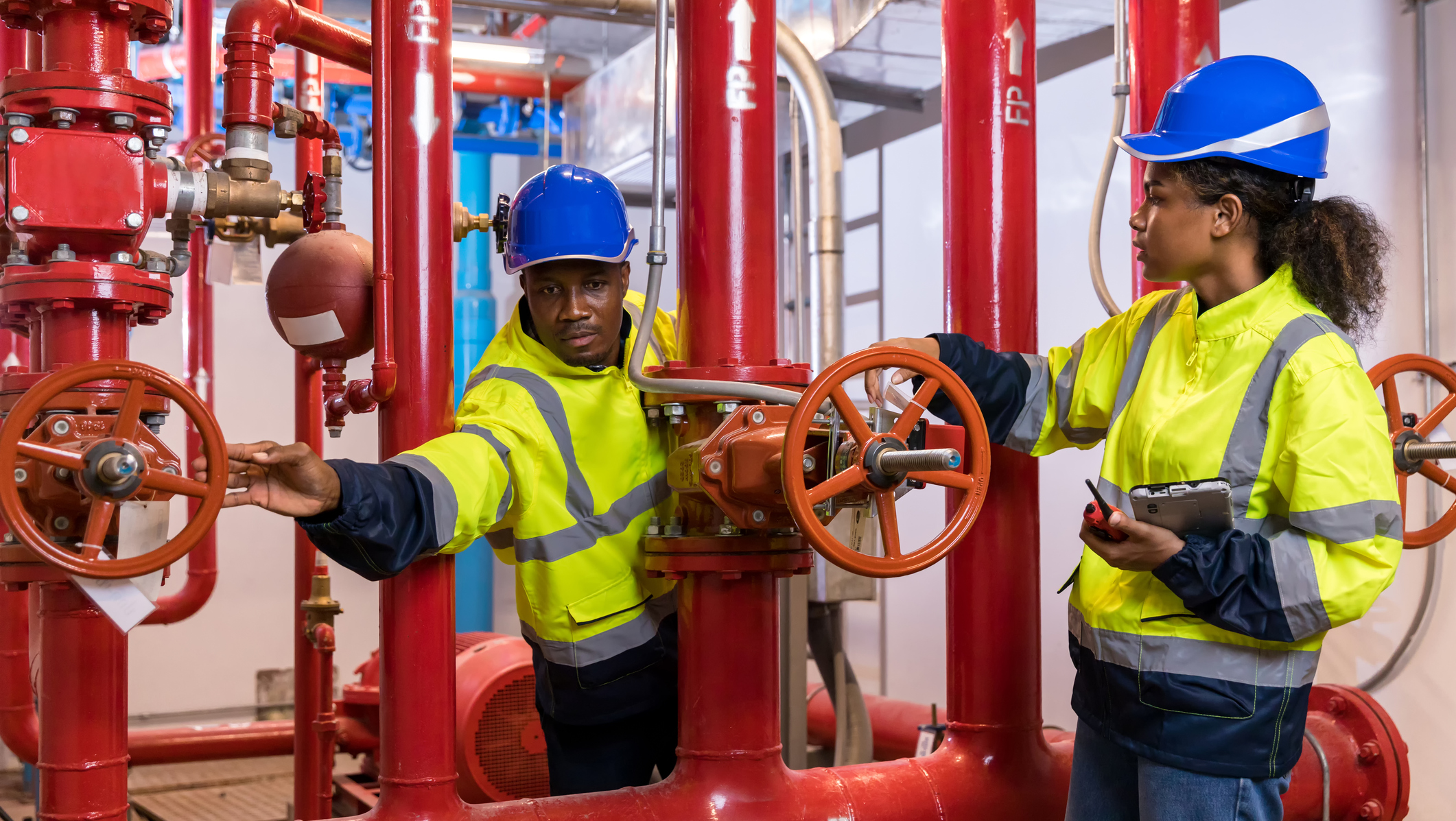 Workers adjusting valves in industrial setting.