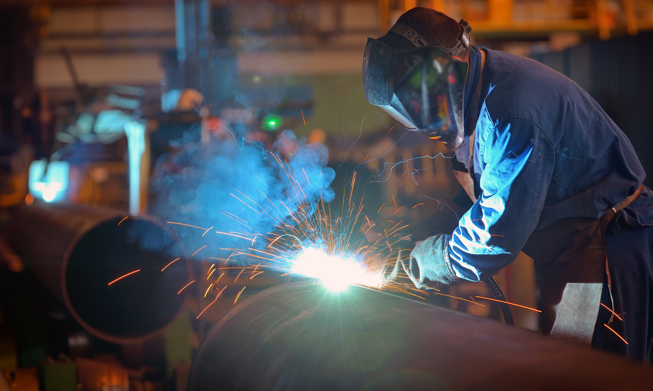 Welder working on large metal pipe.