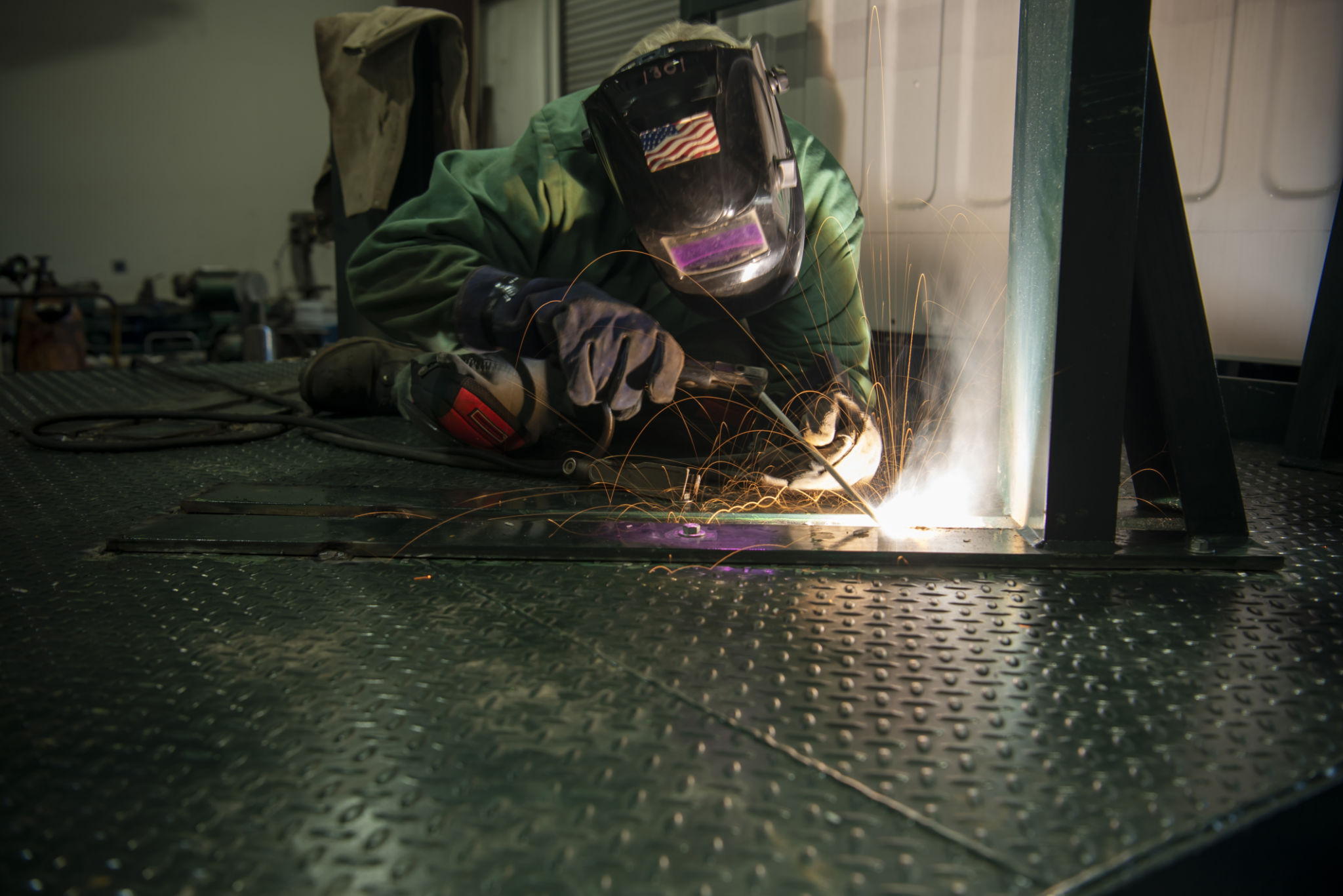 Welder working with protective gear and sparks.